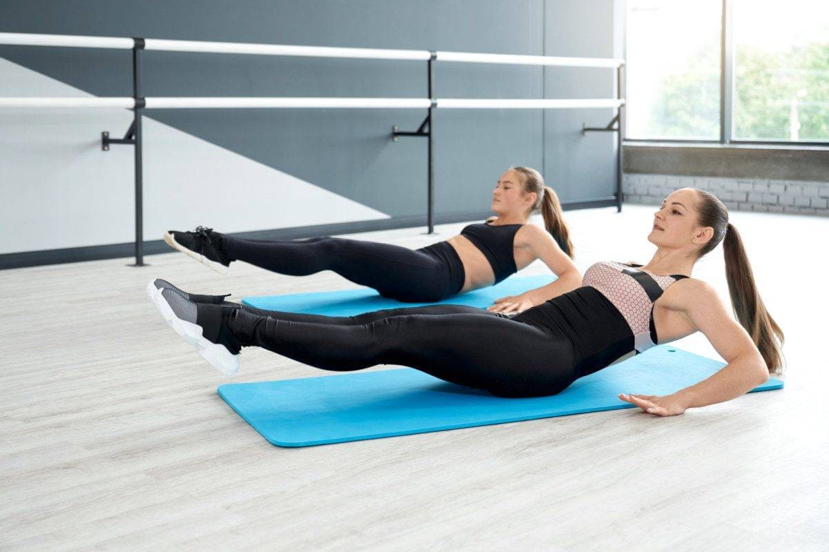 Women training abdominal muscles on mats in studio.