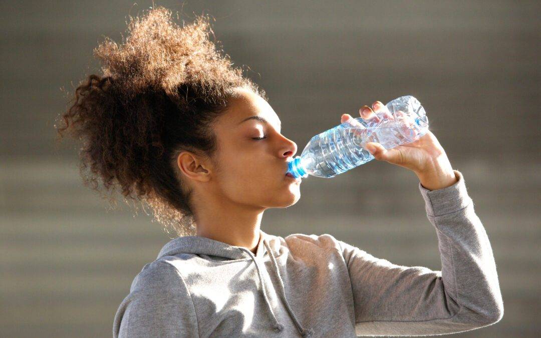 a young woman drinking water from a bottle