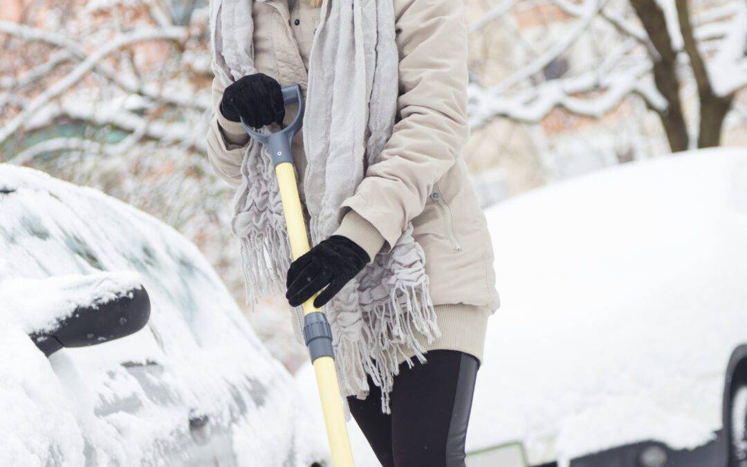Independent woman shoveling her parking lot after a winter snowstorm.