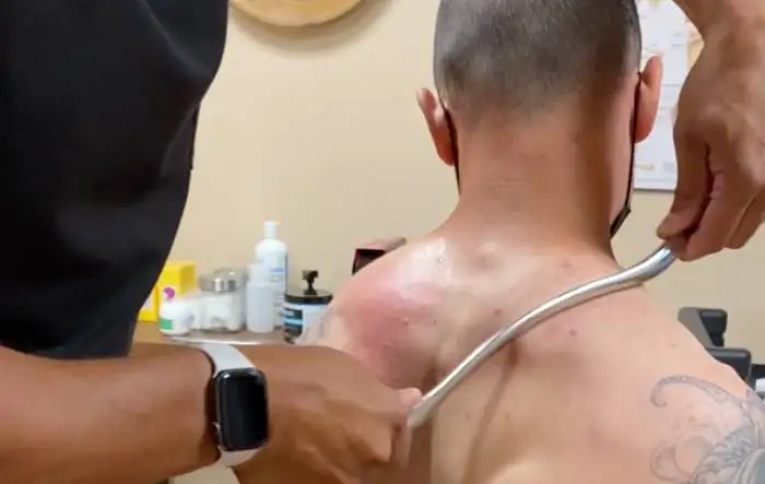 a man is getting his back scanned by a doctor A Patient Getting Back Treatment With Graston Technique