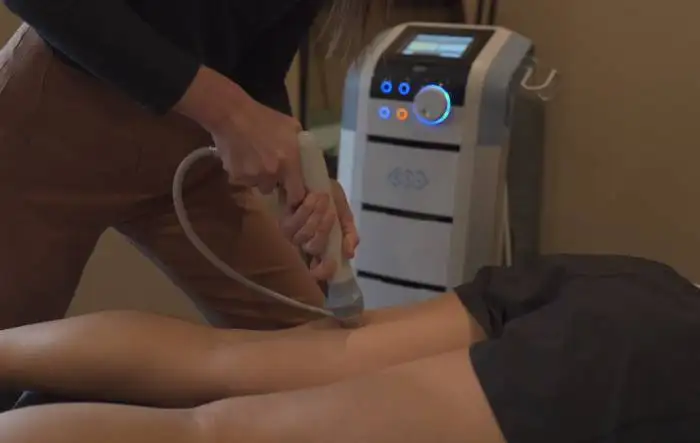 a woman is getting a massage on her leg Leg Treatment With Shockwave Therapy